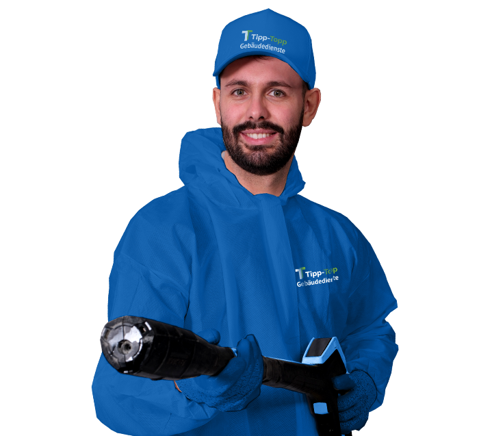 Ein Mitarbeiter für Fassadenreinigung in blauer Arbeitskleidung mit Hochdruckreiniger